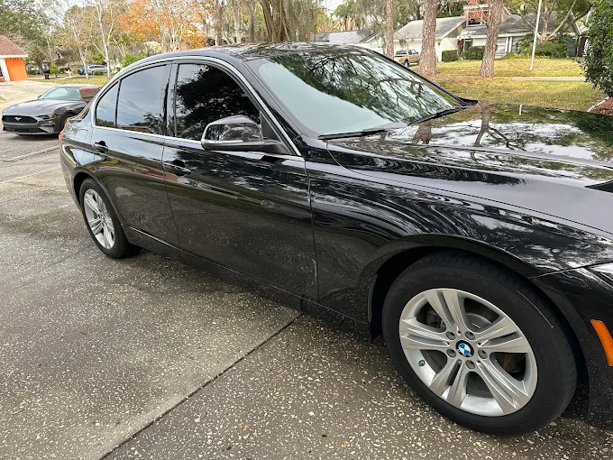 Freshly detailed black BMW 3 Series with reflective paint in a Lutz, Florida driveway